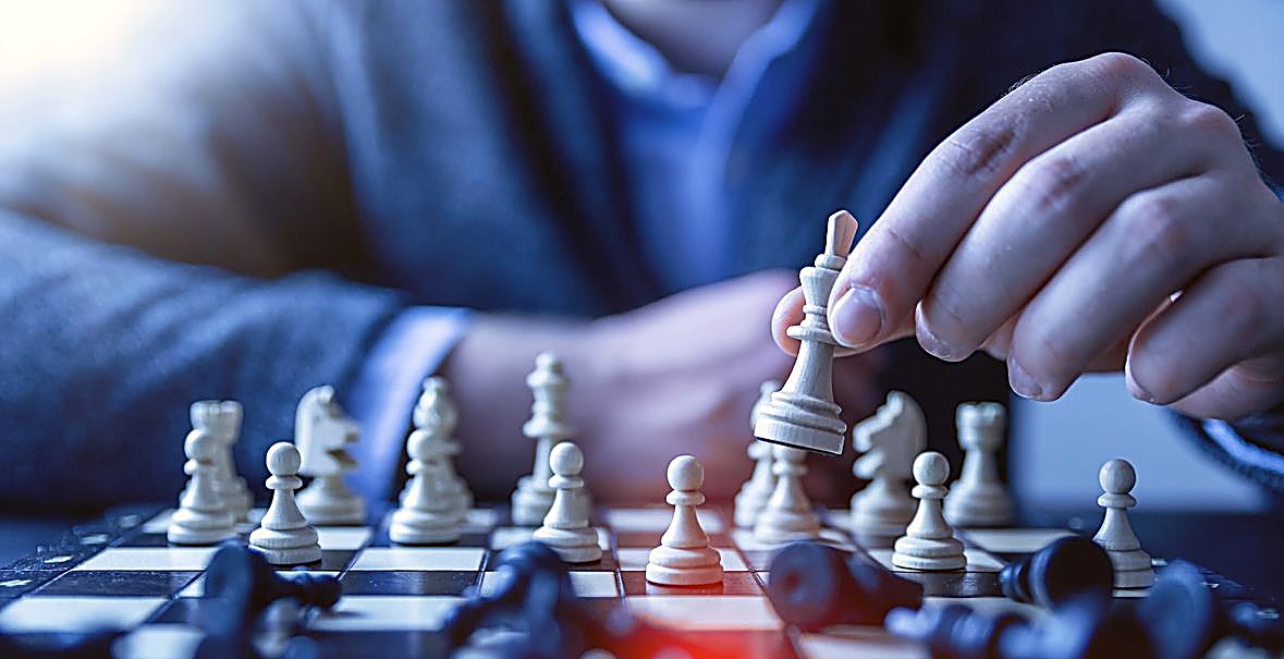 A hand moving a chess piece across a board mid-game