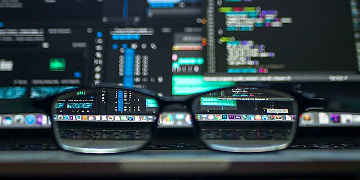 Eyeglasses in focus in front of blurred screens of code