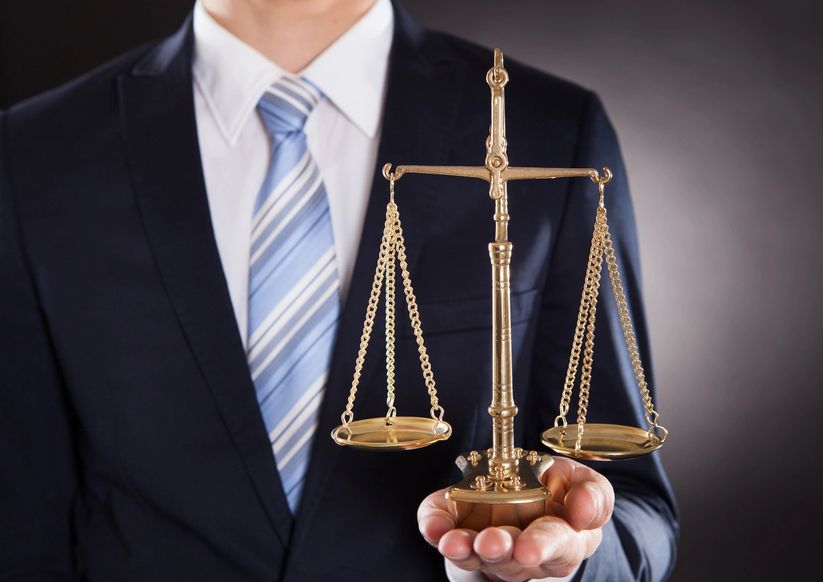 A businessperson holding a balanced brass scale